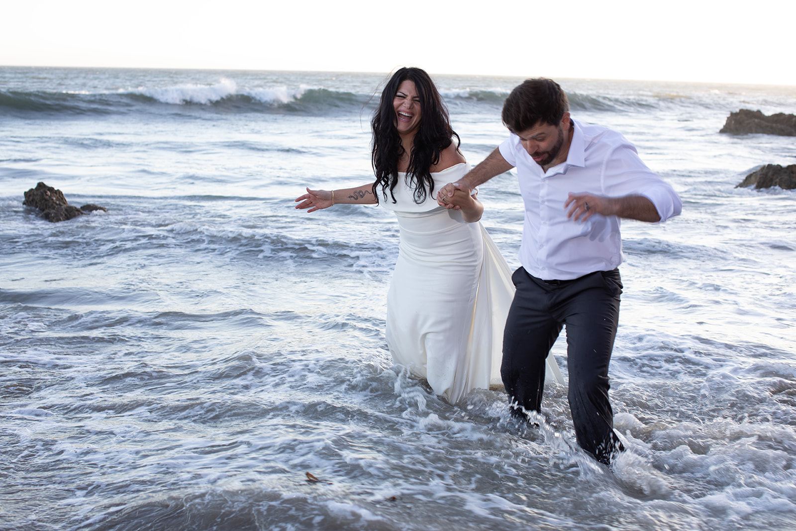 Cam and Sari running hand in hand through the surf